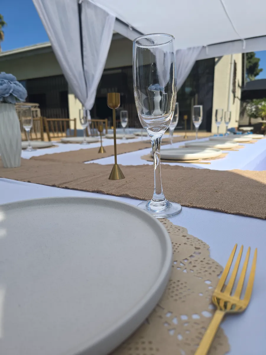 Champagne flute and gold candlesticks on a hessian table runner