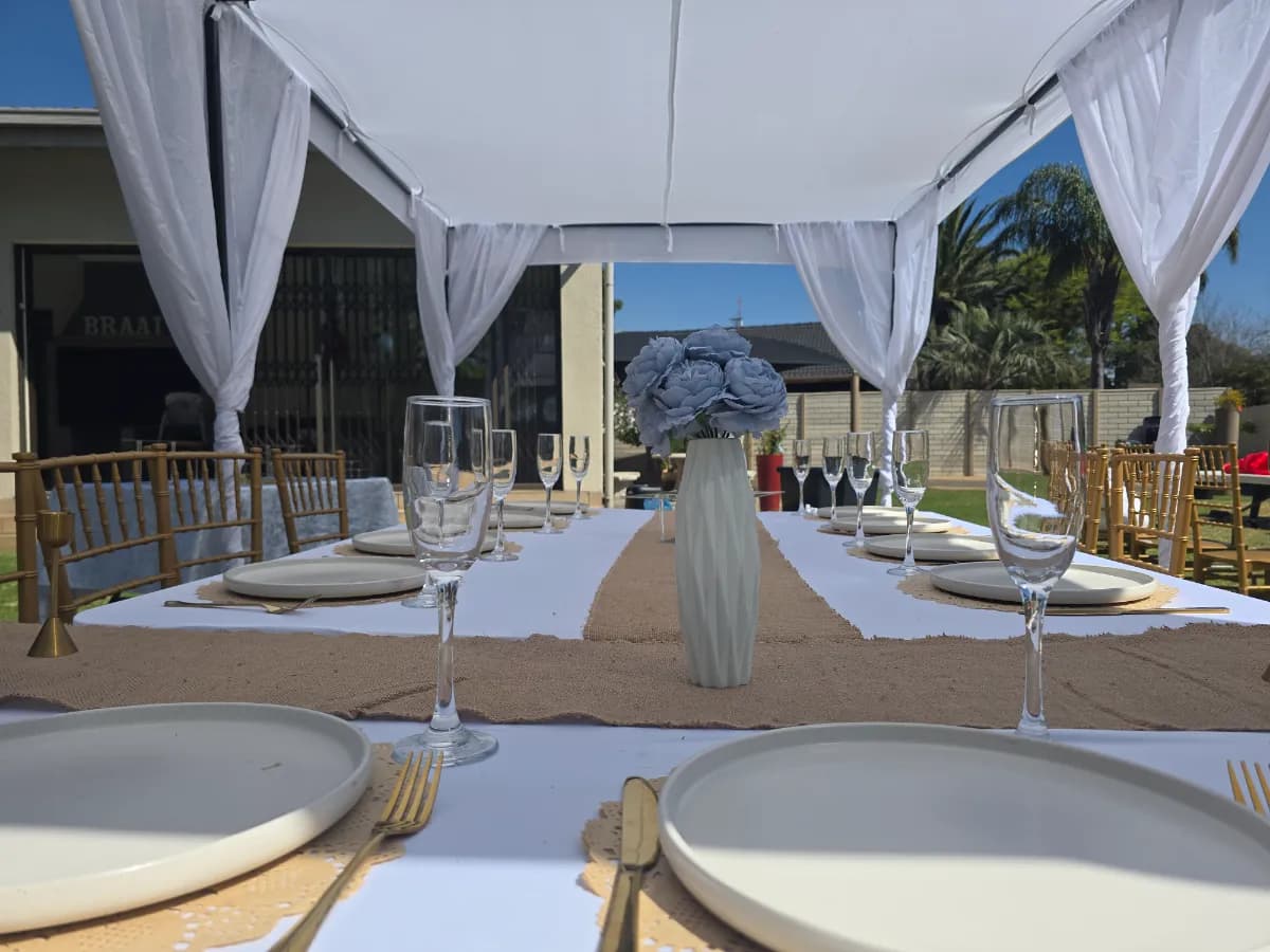 Long table under a white cabana tent with gold chairs