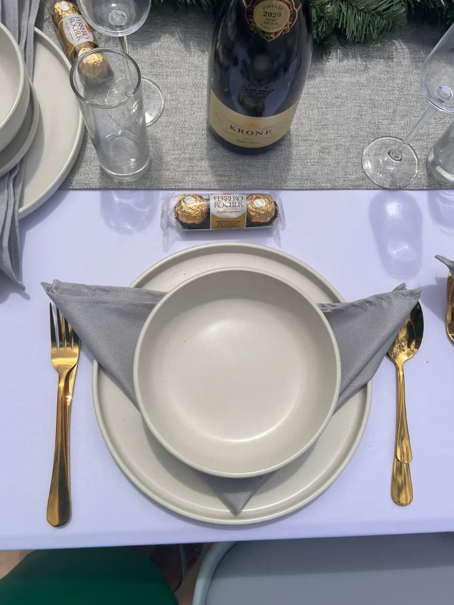 Place setting with a grey napkin, stoneware bowl and gold cutlery