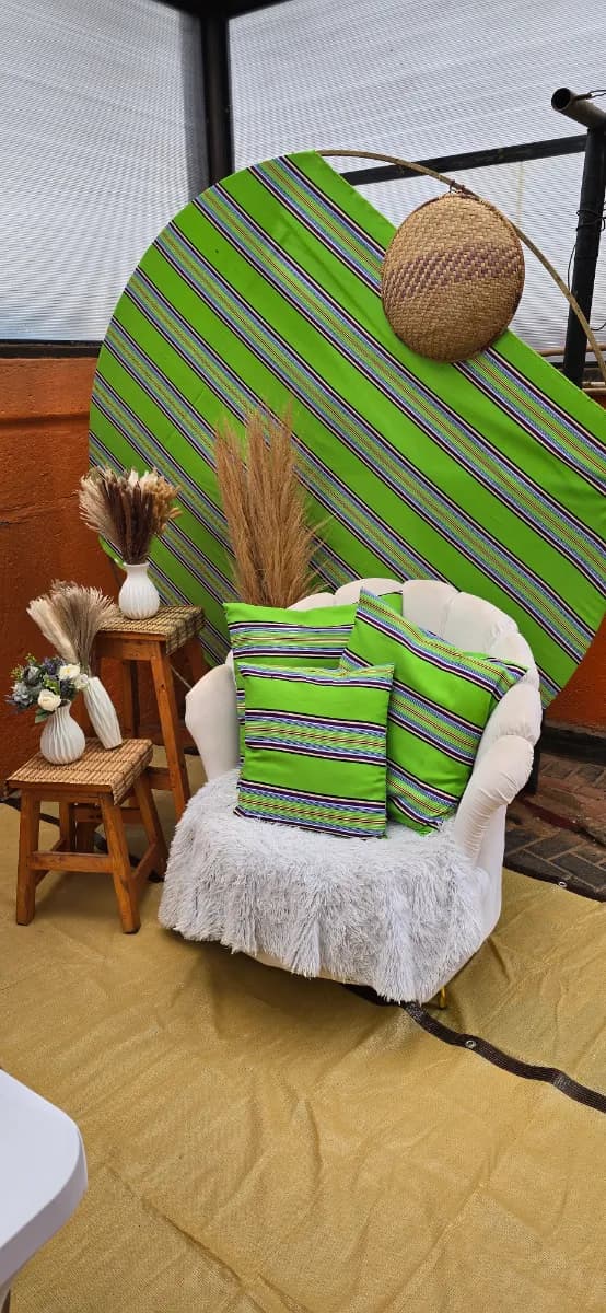 White armchair with green striped cushions before a round striped backdrop